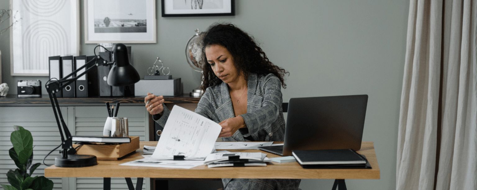 Eine Frau am Schreibtisch bei der Durchsicht von Dokumenten 